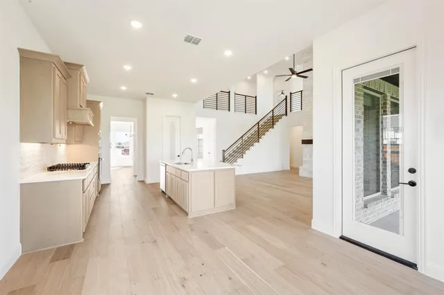 a view of large kitchen with kitchen island a sink wooden floor and a large window