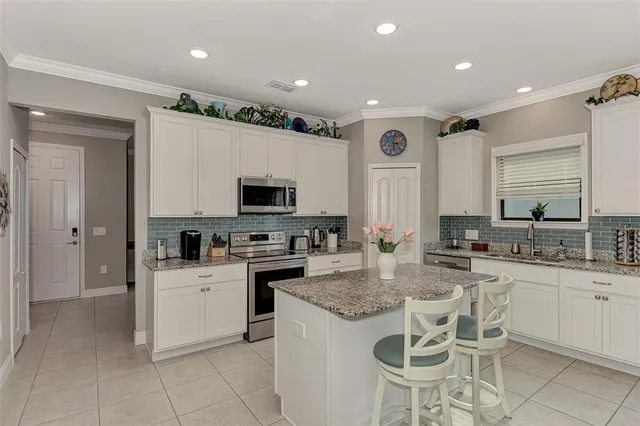 a kitchen with stainless steel appliances granite countertop a stove top oven a sink dishwasher and white cabinets with wooden floor