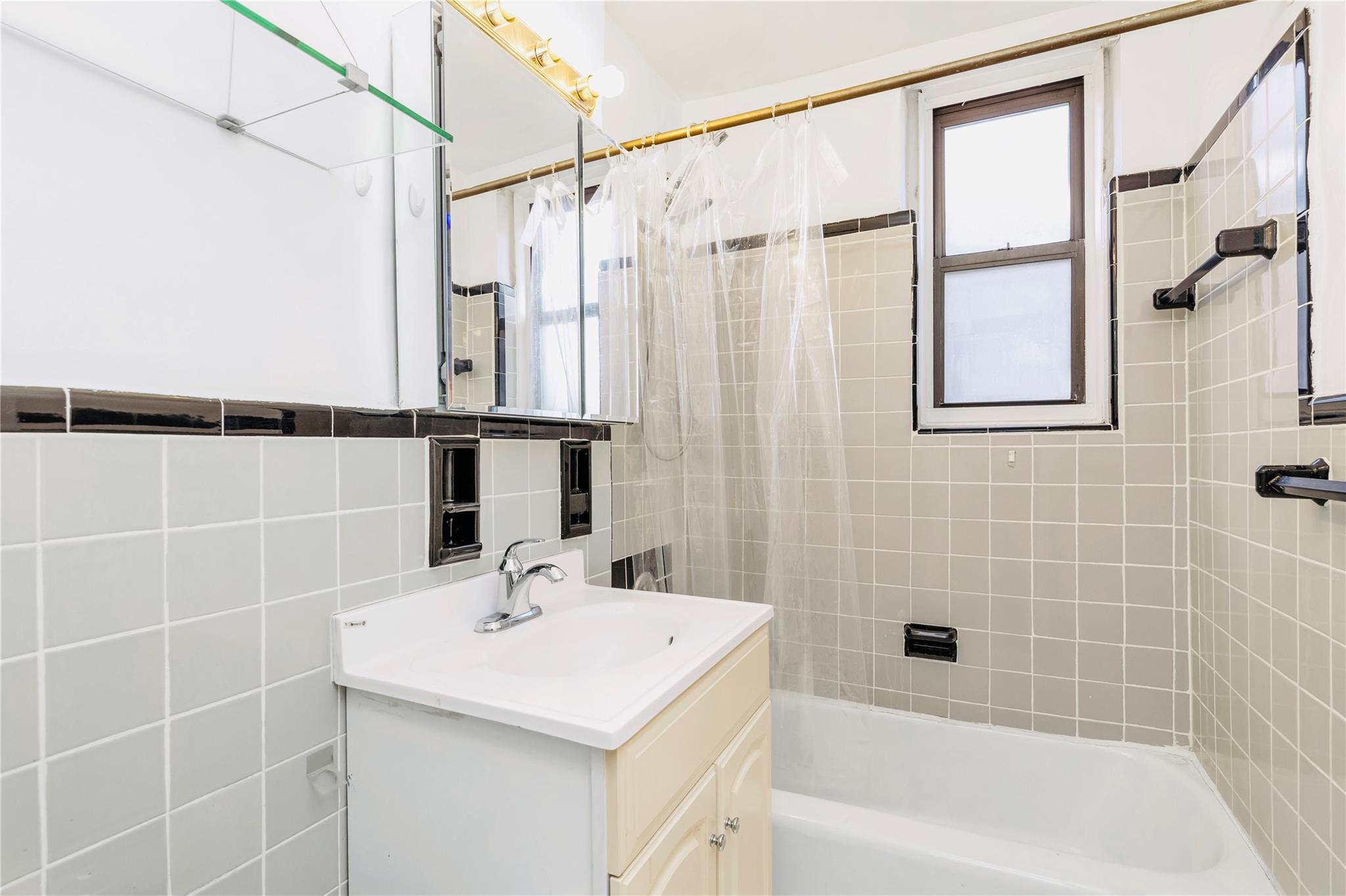 141-05 Pershing Crescent, Unit 511 Queens, NY 11435 - Photo 13 of 14 a bathroom with a sink a mirror and a bathtub