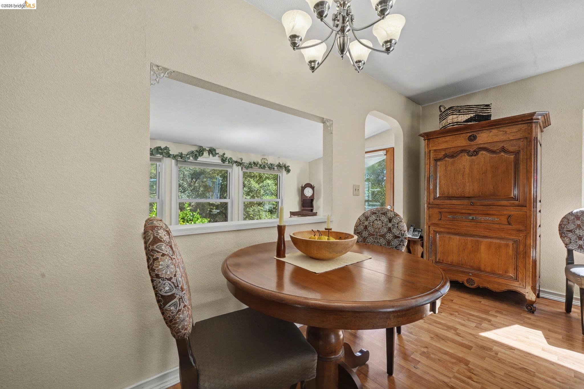 7035 Old Gulch Road San Andreas, CA 95249 - Photo 11 of 45 Dining room featuring a textured wall, light wood finished floors, arched walkways, and a chandelier
