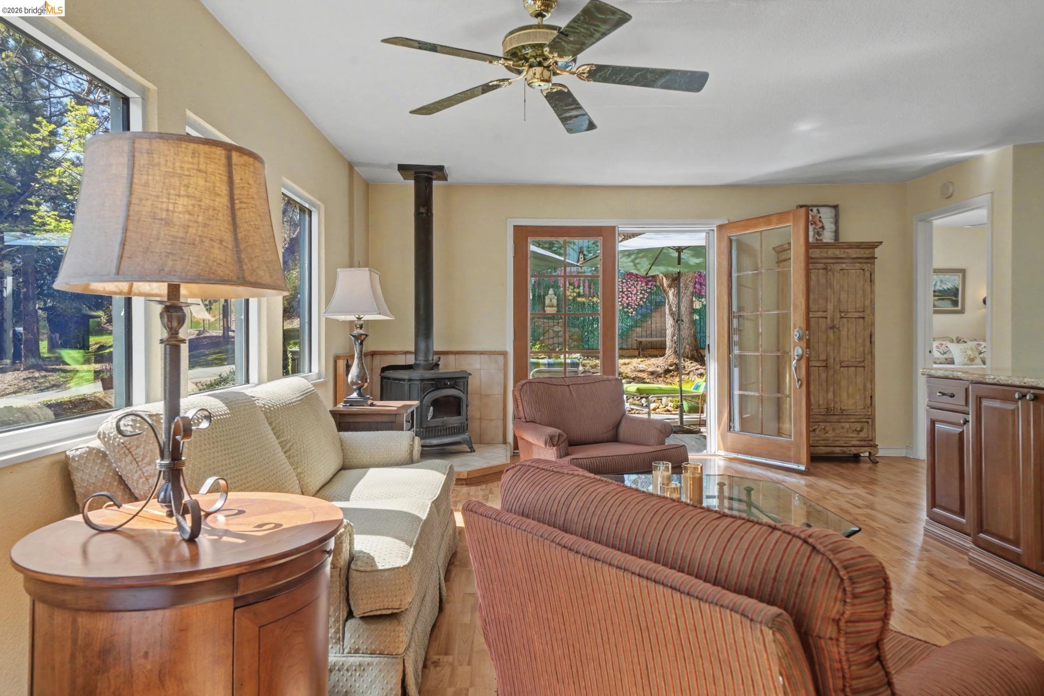 7035 Old Gulch Road San Andreas, CA 95249 - Photo 13 of 45 Living area featuring a wood stove, light wood-style floors, a ceiling fan, and healthy amount of natural light