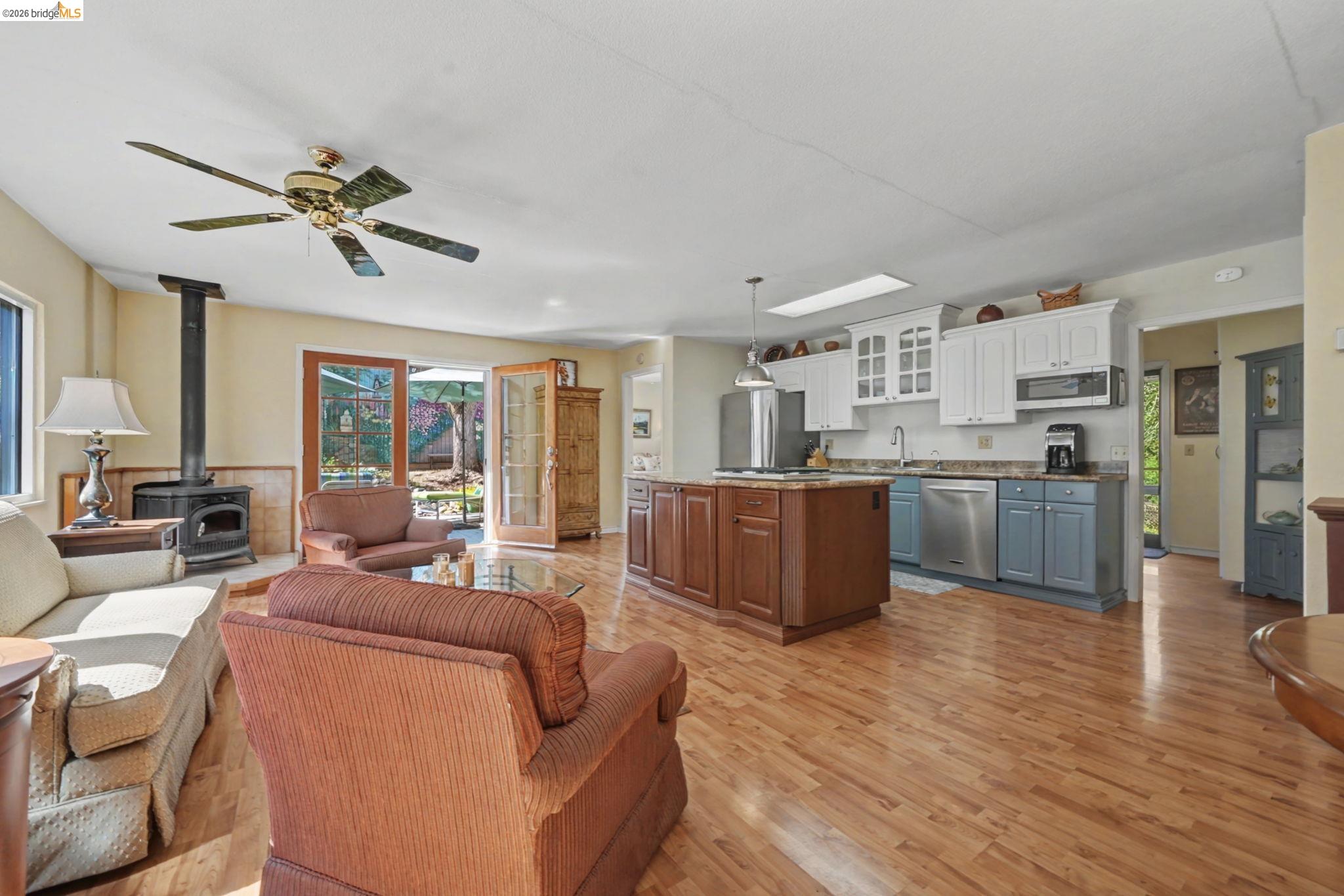 7035 Old Gulch Road San Andreas, CA 95249 - Photo 14 of 45 Living room with a wood stove, light wood-type flooring, and a ceiling fan