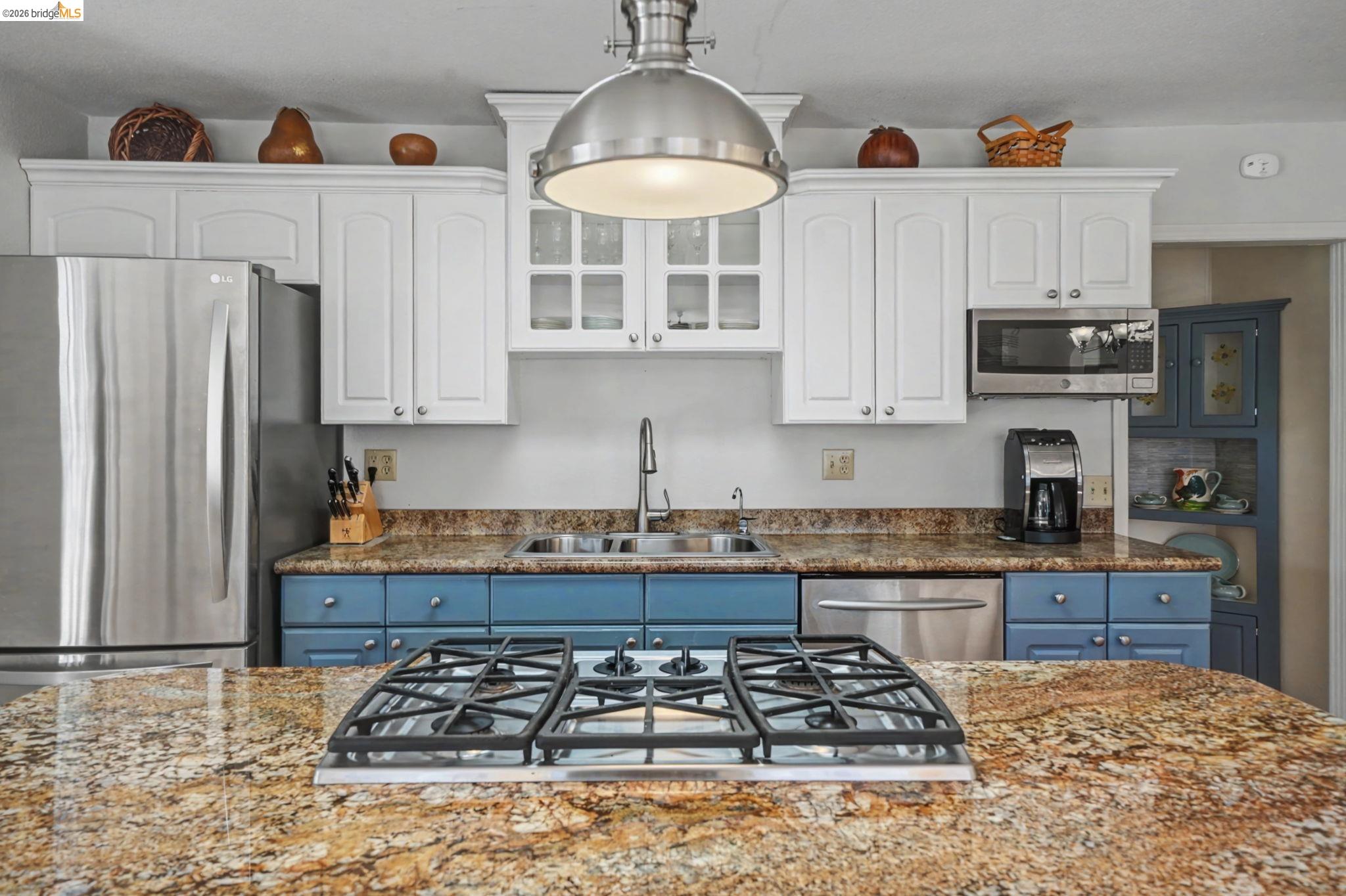 7035 Old Gulch Road San Andreas, CA 95249 - Photo 16 of 45 Two tone kitchen featuring two tone color scheme, stainless steel appliances, glass fronted cabinets, dark stone countertops, and decorative light fixtures
