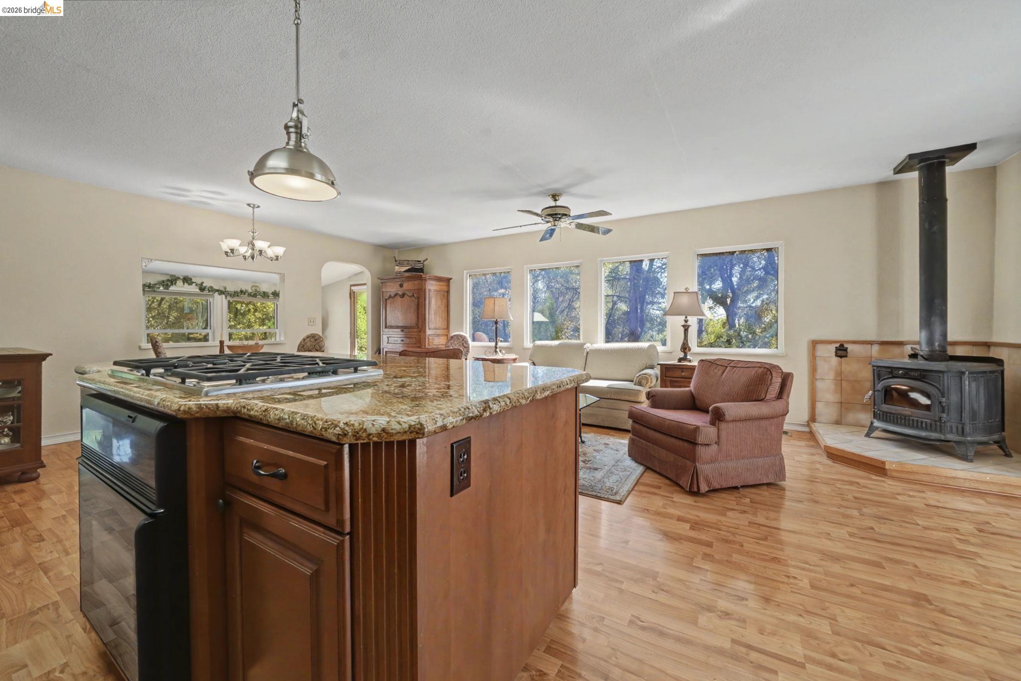 7035 Old Gulch Road San Andreas, CA 95249 - Photo 45 of 45 Kitchen featuring open floor plan, light wood finished floors, a wood stove, light stone counters, and a kitchen island