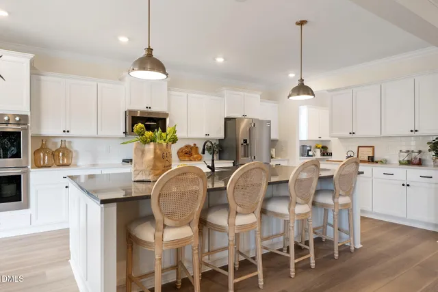 a kitchen with stainless steel appliances kitchen island granite countertop a dining table chairs and white cabinets