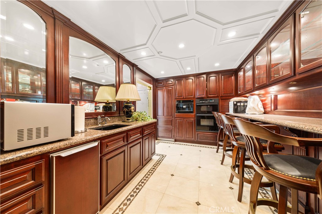 1782 Chota Road La Habra Heights, CA 90631 - Photo 47 of 74 a kitchen with stainless steel appliances kitchen island granite countertop a table chairs in it and wooden floors