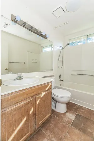 a bathroom with a bathtub shower sink mirror and toilet