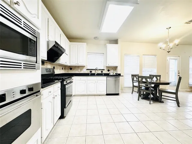 a kitchen with granite countertop cabinets a sink a counter space and stainless steel appliances