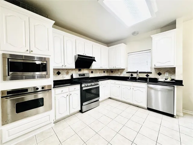 a kitchen with granite countertop white cabinets and appliances