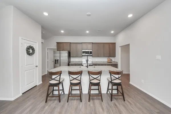 a kitchen with stainless steel appliances kitchen island granite countertop a dining table chairs and white cabinets