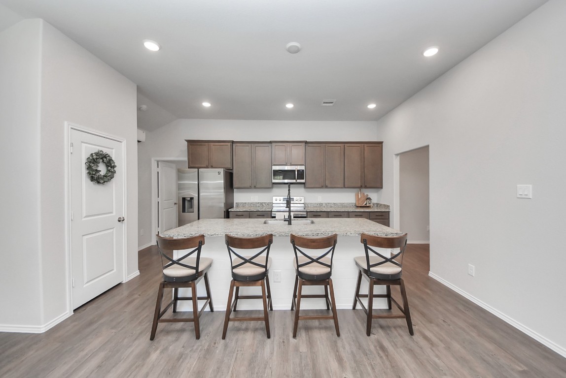 709 Little River Drive Montgomery, TX 77316 - Photo 13 of 40 a kitchen with stainless steel appliances kitchen island granite countertop a dining table chairs and white cabinets