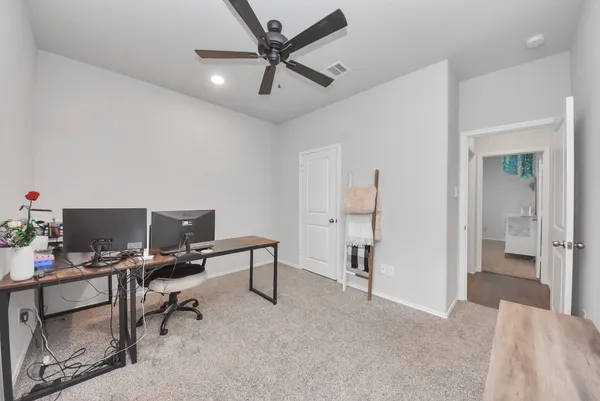 a view of a workspace with furniture and a ceiling fan