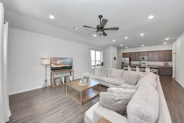 a living room with furniture a kitchen view and a flat screen tv