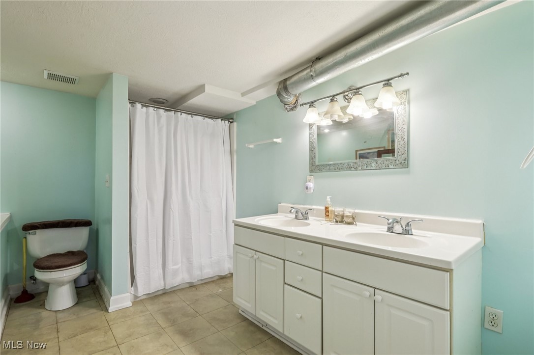 23 Lane Street Rittman, OH 44270 - Photo 9 of 34 Bathroom with double vanity, light tile patterned floors, and curtained shower