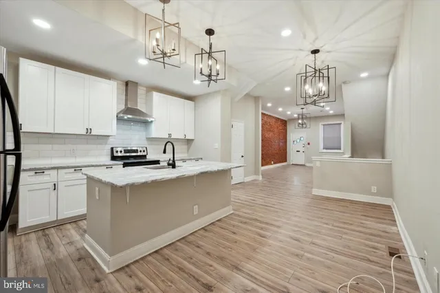 a large kitchen with kitchen island stainless steel appliances a chandelier and wooden floor