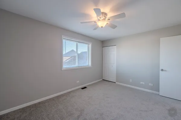 an empty room with a chandelier fan and windows