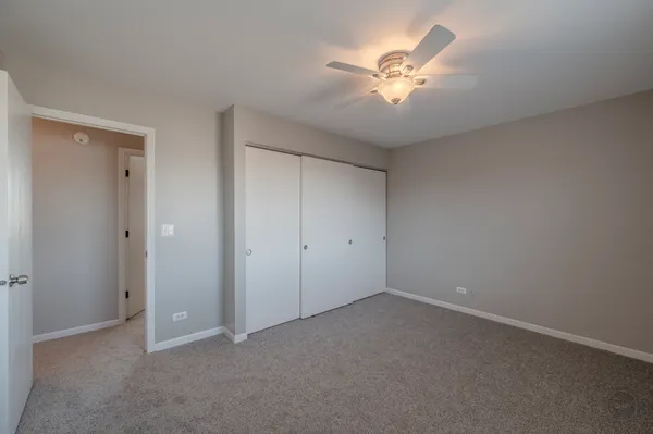 an empty room with closet and a ceiling fan