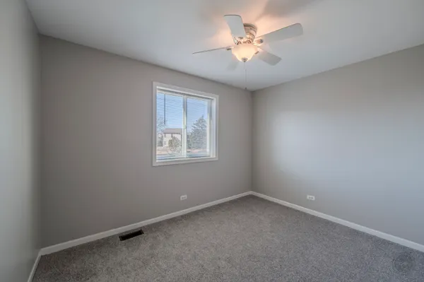 an empty room with a chandelier fan and windows