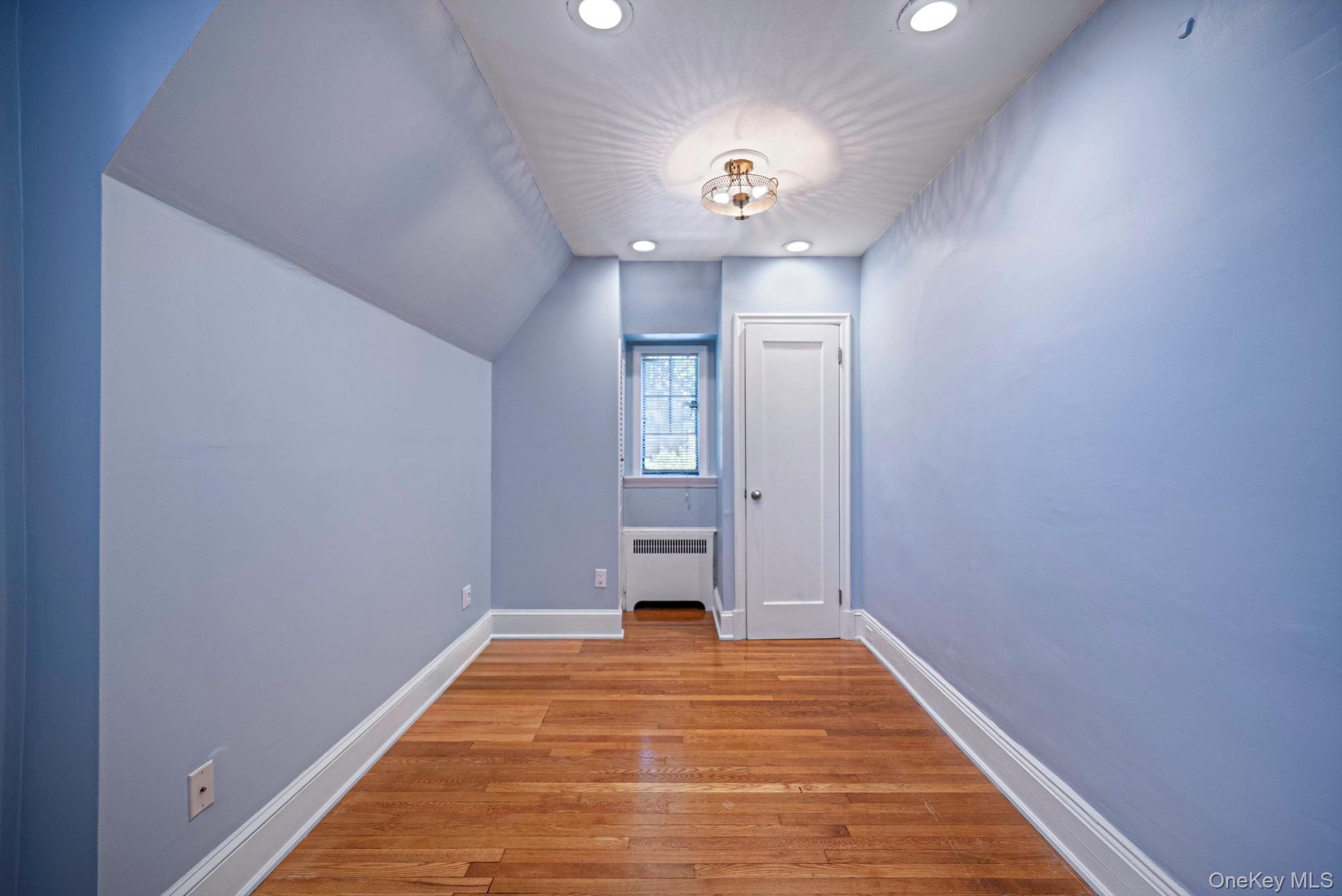 18240 Avon Road Queens, NY 11432 - Photo 19 of 30 Hardwood flooring and recessed lighting illuminate this interior space, featuring a window with a radiator below
