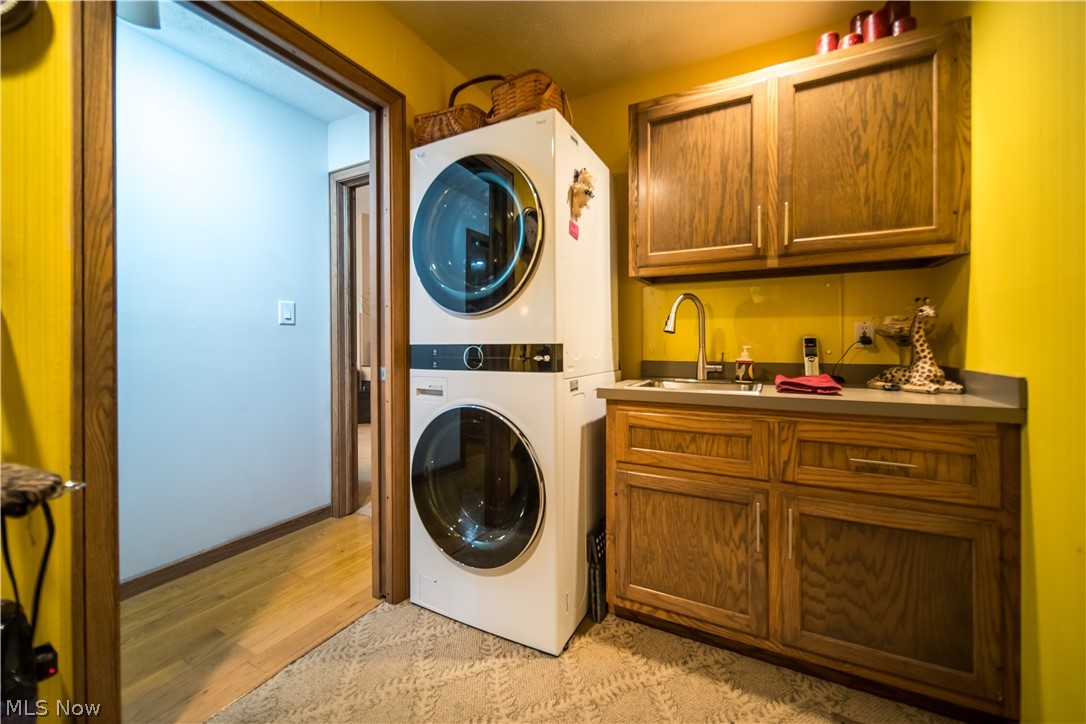 5119 Hattrick Road Ravenna, OH 44266 - Photo 25 of 33 Washroom with stacked washer / dryer, cabinets, sink, and light hardwood / wood-style flooring
