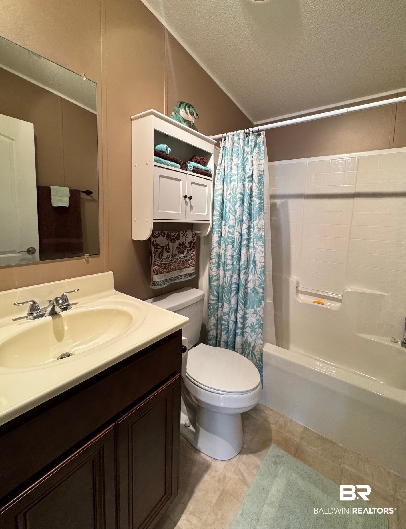 1165 Santa Anna Lane Lillian, AL 36549 - Photo 16 of 43 Full bathroom featuring a textured ceiling, toilet, vanity, vaulted ceiling, and shower / bath combination with curtain