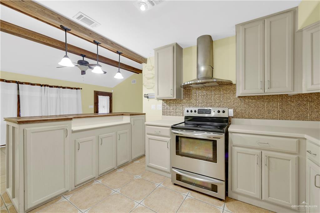 1815 Thornton Street Mission, TX 78572 - Photo 9 of 27 Kitchen with electric range, wall chimney range hood, tasteful backsplash, decorative light fixtures, and light tile patterned flooring