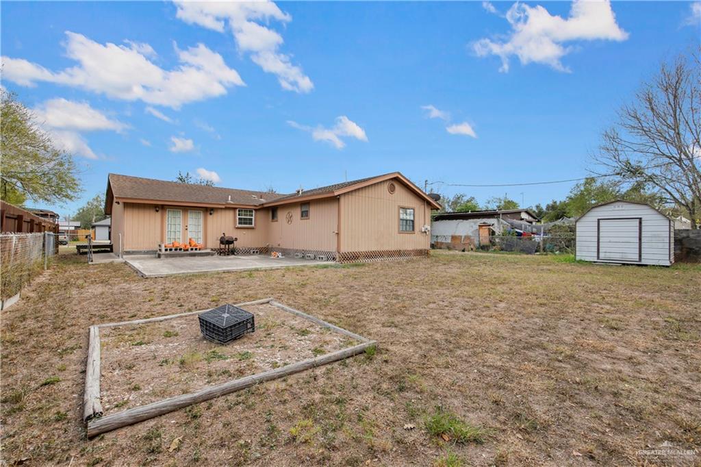 1815 Thornton Street Mission, TX 78572 - Photo 20 of 27 Rear view of house featuring a storage shed, a patio area, a fenced backyard, and a fire pit