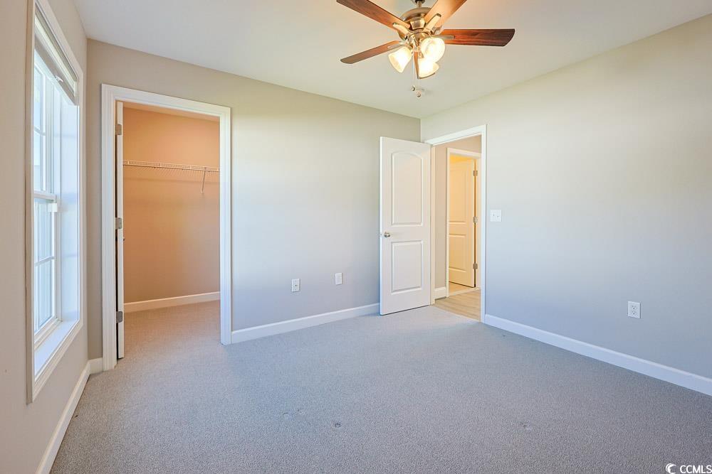 1036 Macala Drive Conway, SC 29527 - Photo 19 of 34 Unfurnished bedroom with a walk in closet, light carpet, and a ceiling fan