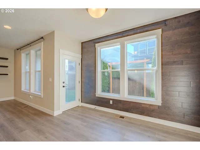 a view of an empty room with wooden floor and windows