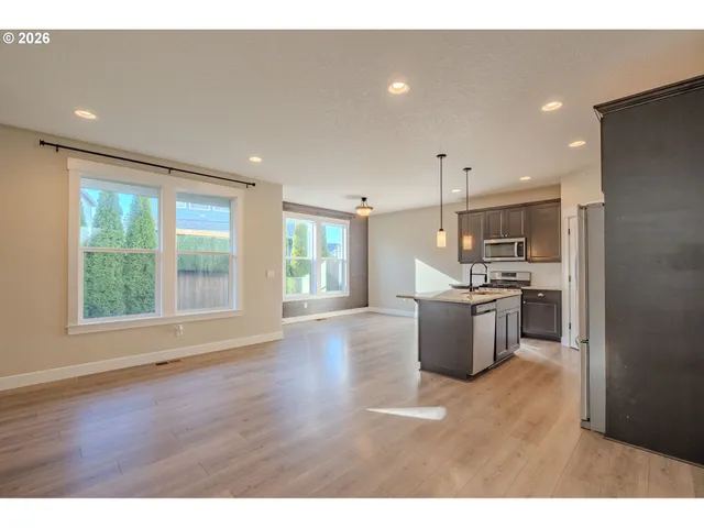 a kitchen with stainless steel appliances kitchen island granite countertop a stove a sink a refrigerator a window and a dining table