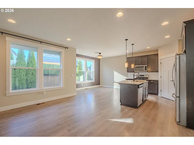 a open kitchen with stainless steel appliances granite countertop a refrigerator a sink dishwasher a stove and a large countertops with wooden floor