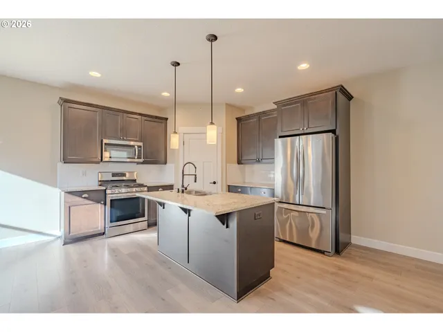 a kitchen with stainless steel appliances granite countertop a refrigerator a sink dishwasher a stove with white cabinets