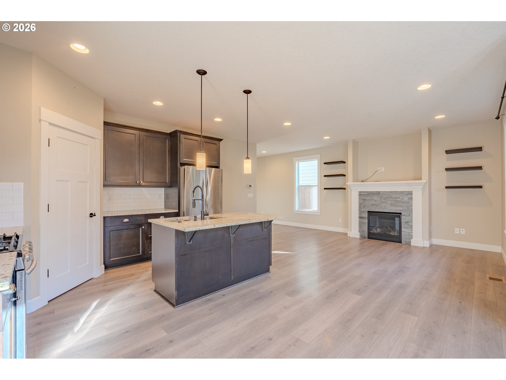 1145 South Quail Run Place Ridgefield, WA 98642 - Photo 10 of 41 a open kitchen with kitchen island a stove a refrigerator a sink dishwasher and a fireplace with wooden floor
