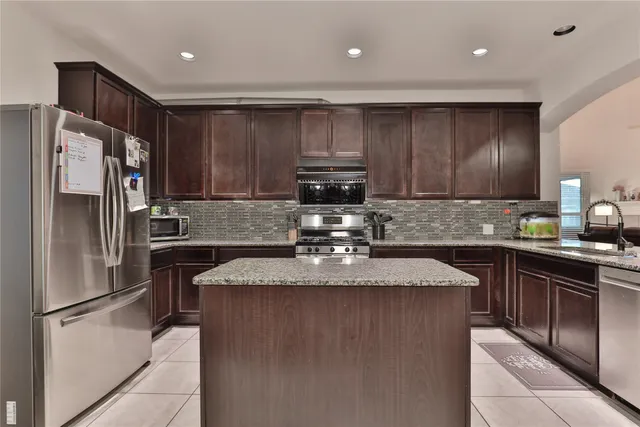 a kitchen with granite countertop stainless steel appliances and a refrigerator