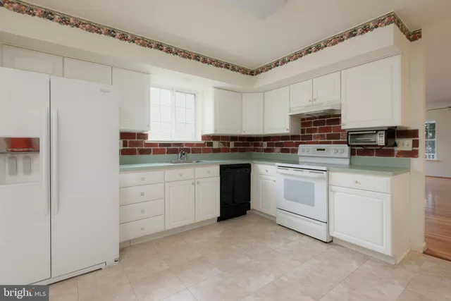 a kitchen with white cabinets stainless steel appliances and a window
