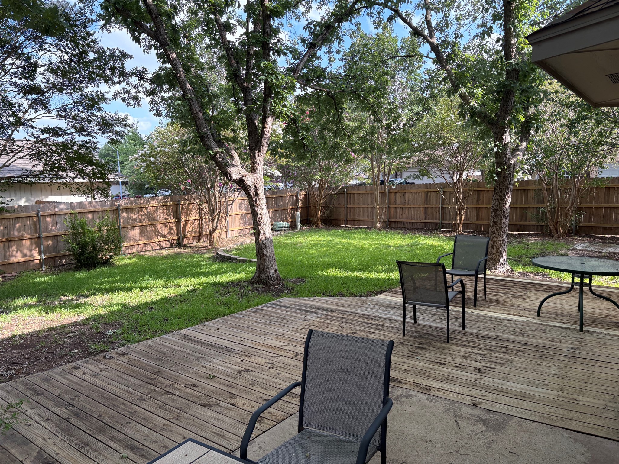 14707 Single Trace Austin, TX 78728 - Photo 6 of 17 A well-maintained wooden fence encloses a lush, green yard with mature trees, providing a private outdoor retreat.