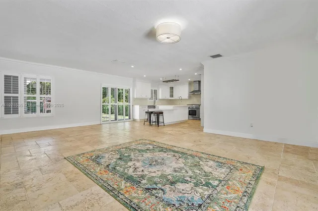 an empty room with kitchen view and wooden floor