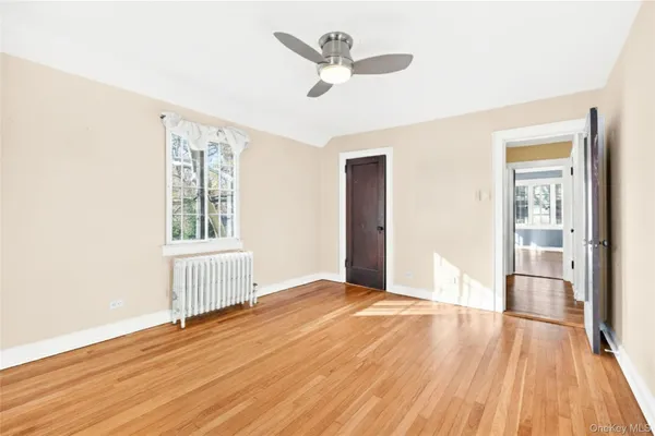 a view of an empty room with a window and wooden floor