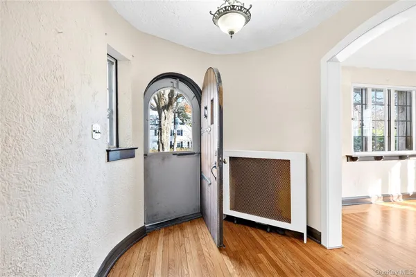 an empty room with wooden floor mirror and windows
