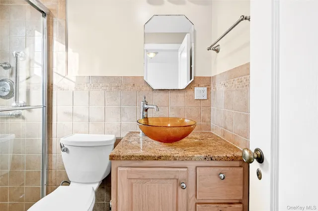a bathroom with a granite countertop toilet sink and mirror