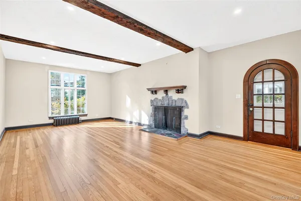 a view of an empty room with window and wooden floor