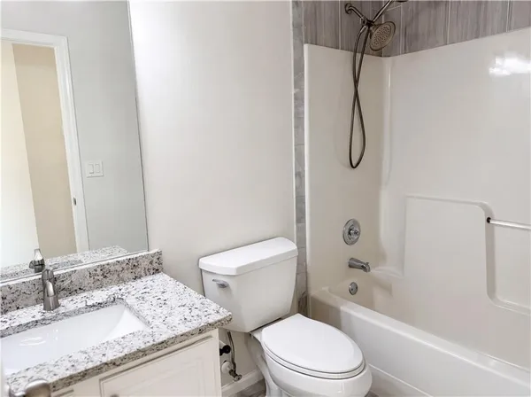 a bathroom with a granite countertop sink toilet and shower