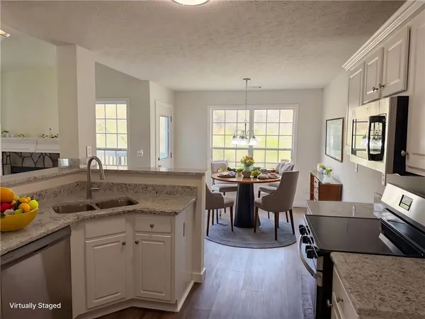 a kitchen with stainless steel appliances granite countertop a stove a sink dishwasher a refrigerator a dining table and chairs with wooden floor