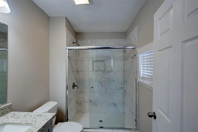 a bathroom with a granite countertop shower and a toilet