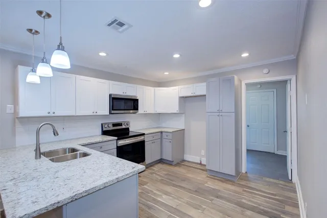 a kitchen with a sink stainless steel appliances and wooden floor