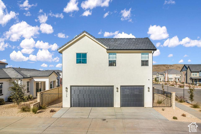 636 Phase 6 Street St. George, UT 84790 - Photo 5 of 16 Stucco exterior featuring a dark tile roof, two garage bays with dark doors, and exterior wall sconces