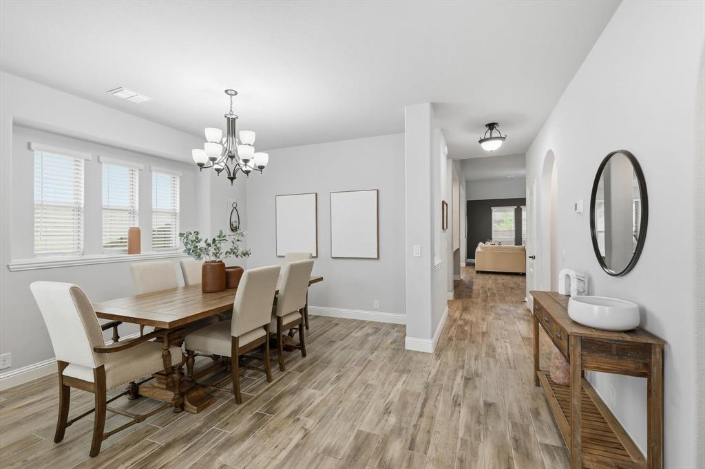 924 Timber Ridge Drive Justin, TX 76247 - Photo 7 of 32 Dining area with wood-finish flooring, a multi-light chandelier, and multiple windows with blinds