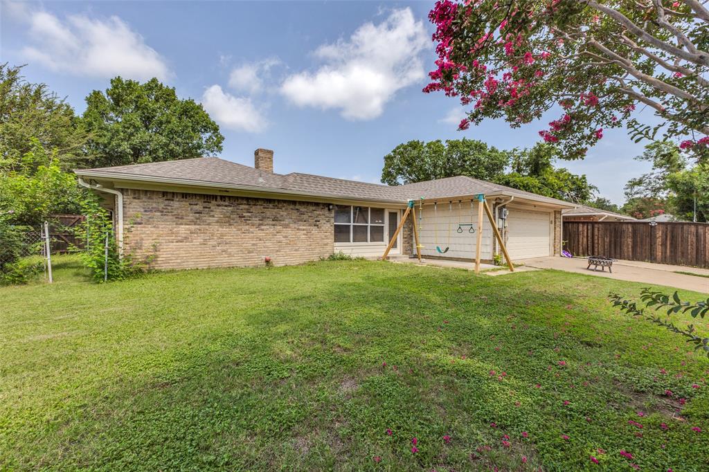705 South Grove Road Richardson, TX 75081 - Photo 24 of 26 Brick exterior with an attached two-car garage, featuring a paved driveway, a green lawn, and a privacy fence