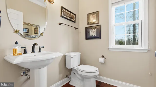 a bathroom with a sink a mirror a toilet and a window