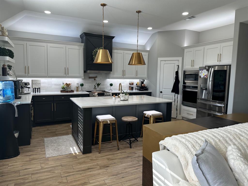 351 Mesa Ridge Decatur, TX 76234 - Photo 4 of 29 Kitchen featuring stainless steel appliances, a breakfast bar area, a kitchen island, light wood-style flooring, and backsplash